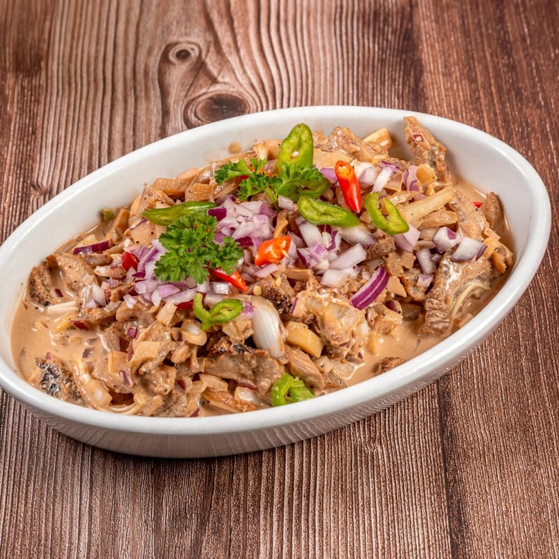 Filipino Bopis, a dish with minced pork and lungs in a creamy sauce, garnished with chilies and onions.