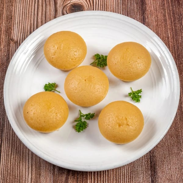 Five golden-brown Filipino puto, steamed rice cakes, arranged on a white plate with parsley garnishes.