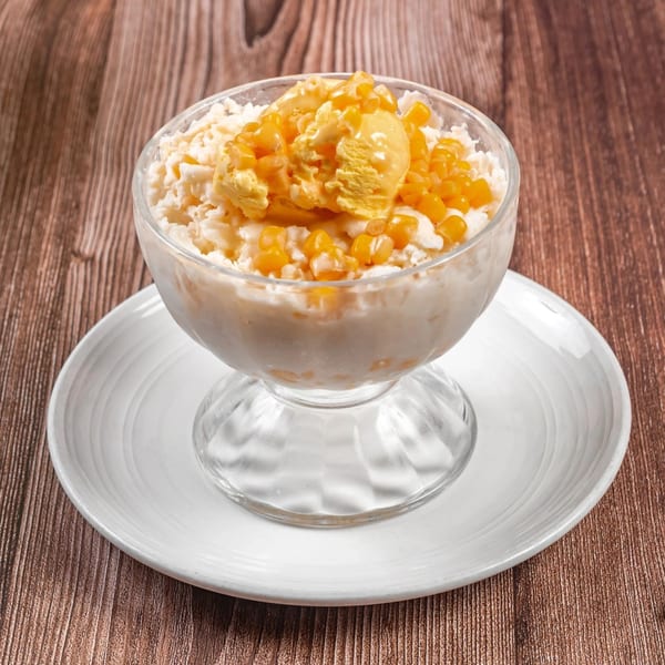 Filipino dessert Mais con Yelo, a glass of shaved ice, corn kernels, and a scoop of ice cream.