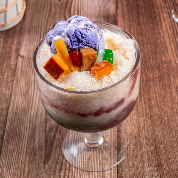 Halo-Halo dessert in a glass, topped with purple ube ice cream, jackfruit, and other colorful Filipino sweets.