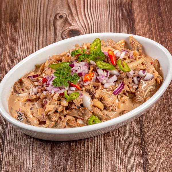 Filipino Bicol Express, a creamy pork dish with coconut milk, chili, and onions in a white bowl.