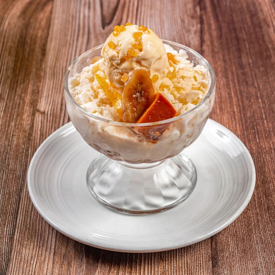 Filipino Halo-Halo dessert in a glass, topped with ice cream, fruit, and boba pearls.