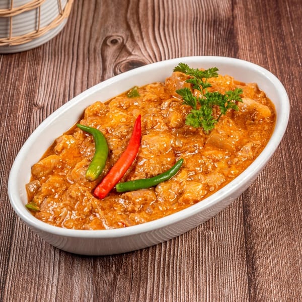 Filipino Bicol Express, a spicy pork dish in coconut milk, garnished with red and green chilies.